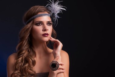 1920 'lerin tarzında giyinmiş güzel bir genç kız. Geçmişe dönük aksesuarları olan genç bir kadın.