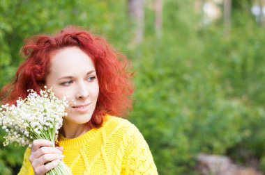 Sarı süveterli, beyaz çiçekli, kızıl saçlı, nazik genç bayanı kapatın. Gün ışığındaki kız