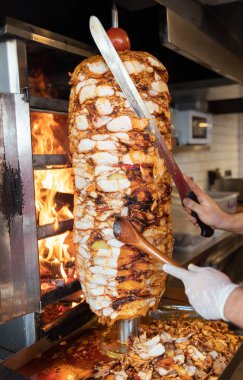 Aşçı, geleneksel Türk Donör Kebap etiyle kesiyor. Shawarma veya jiroskoplar. Türkçe, Yunanca ya da Ortadoğu tarzında izole edilmiş beyaz kebap.