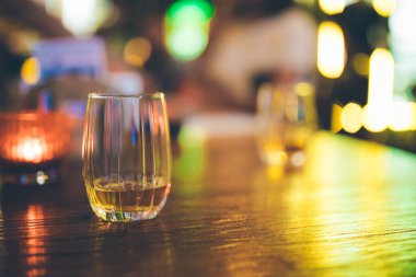 Geceleri pub, bar veya restoranda ahşap masada tek bardak viski veya viski. Tahta masada viski, burbon veya İrlanda viskisi. Gece hayatı konsept görüntüsü