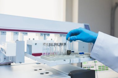 Araştırma görevlisi, doktor, bilim adamı, fizikçi ya da laboratuvar asistanı cam tüpleri tutuyor ve modern laboratuvarda aletler, aletler ve makinelerle çalışıyor, deney yapıyor ve analiz ediyor..