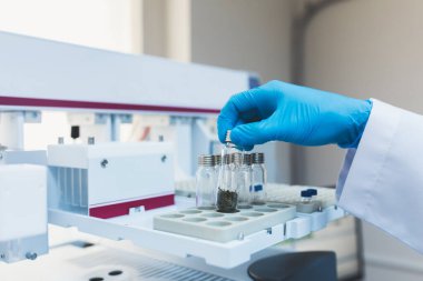 Araştırma görevlisi, doktor, bilim adamı, fizikçi ya da laboratuvar asistanı cam tüpleri tutuyor ve modern laboratuvarda aletler, aletler ve makinelerle çalışıyor, deney yapıyor ve analiz ediyor..