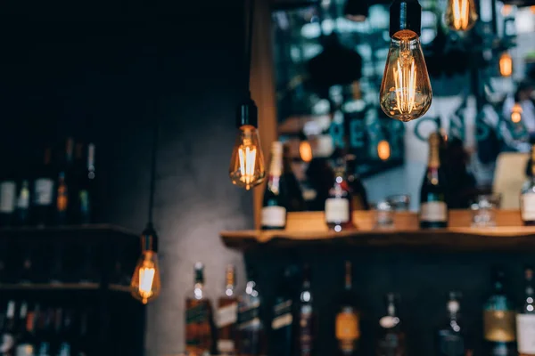 Vintage luxury interior lighting decor in cafe. old Vintage light bulb lamps. Restaurant Bar lighting interior design. Vintage Light bulbs at wine chamber in front of alcoholic drinks bottles