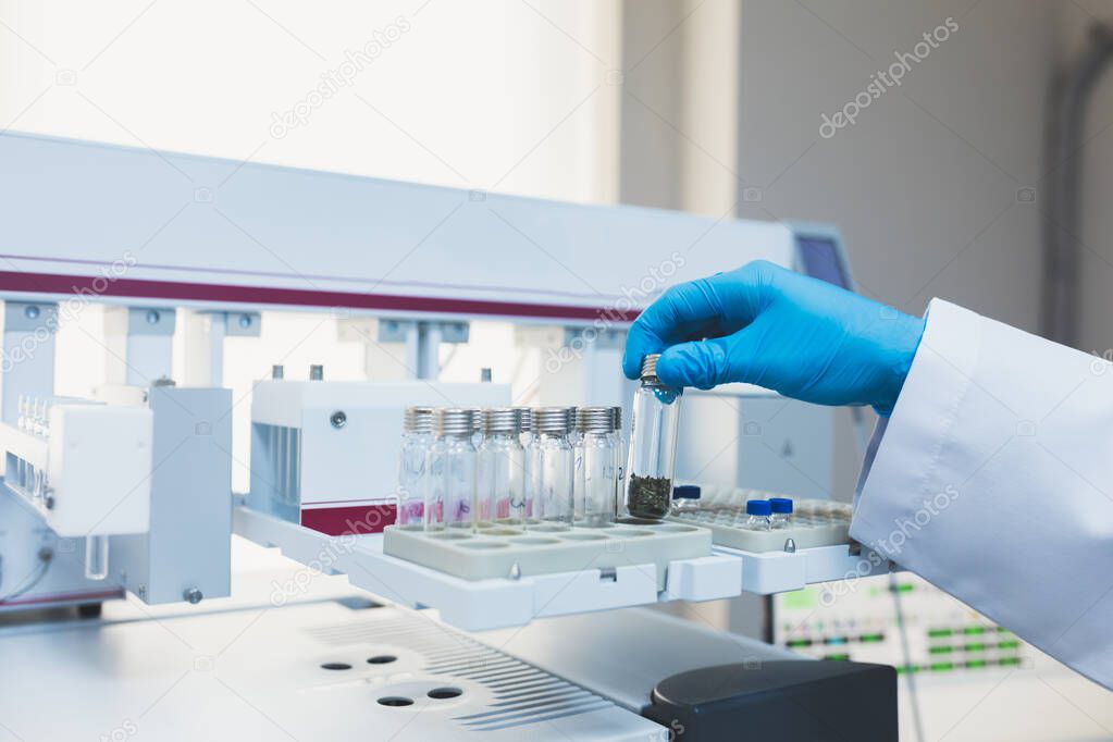 Researcher, doctor, scientist, physicist or laboratory assistant holding test glass tubes and working, experimenting and analyzing in modern lab with equipments, tools and machines.
