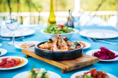 Karides, Deniz Ürünleri, mezeler ve salatalar Fish Restaurant'ta masada. Yunanistan veya Türkiye'de Beach Restaurant. Bodrum, Santorini veya Mikonos'ta Ege sahili, Yunan veya Türk tarzı balık restoranı