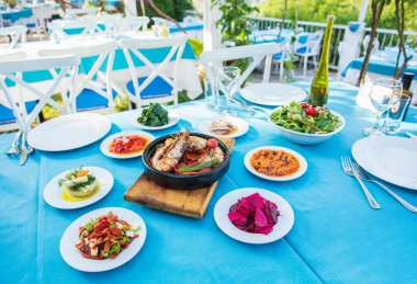 Karides, Deniz Ürünleri, mezeler ve salatalar Fish Restaurant'ta masada. Yunanistan veya Türkiye'de Beach Restaurant. Bodrum, Santorini veya Mikonos'ta Ege sahili, Yunan veya Türk tarzı balık restoranı