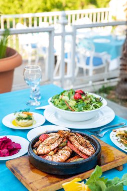 Karides, Deniz Ürünleri, mezeler ve salatalar Fish Restaurant'ta masada. Yunanistan veya Türkiye'de Beach Restaurant. Bodrum, Santorini veya Mikonos'ta Ege sahili, Yunan veya Türk tarzı balık restoranı