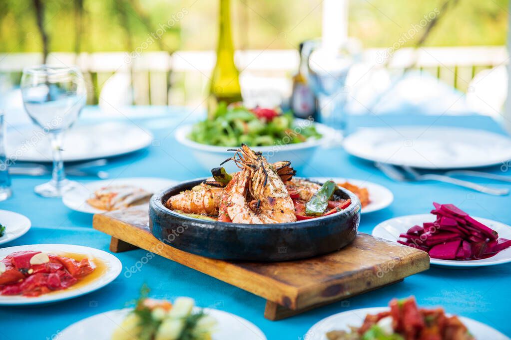 Shrimp, Seafoods, appetizers and salads on the table in Fish Restaurant. Beach Restaurant in Greece or Turkey. Aegean seaside, Greek or Turkish style fish restaurant in Bodrum, Santorini or Mykonos