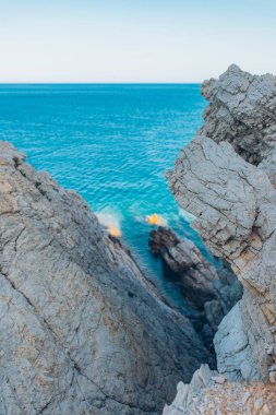 Denizde taş kaya, okyanus ve mavi gökyüzü. Denizin ufku ve mavi temiz gökyüzü.