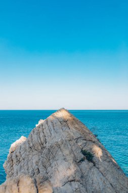 Denizde taş kaya, okyanus ve mavi gökyüzü. Denizin ufku ve mavi temiz gökyüzü.