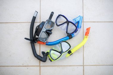 Renkli su geçirmez dalış maskeleri ve şnorkeller havuz zemininde. Mayo konsepti resmi.