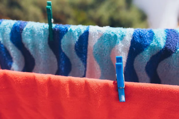 Cleaning and washing clothes. Clean and pure clothes. Clothes pins or pegs on the beach towels. Colorful clothings hanged by plastic pegs.