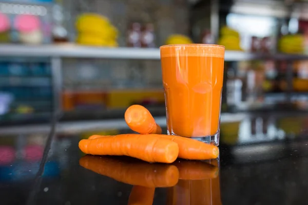 Fresh carrot juice with carrots on the black table