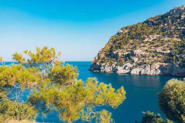 Türkiye 'de güneşli bir günde Akdeniz manzarası. Deniz ve ağaçlarla dolu yaz günü manzarası. Mavi deniz ve dağların gökyüzü manzarası, Akdeniz ya da Ege Denizi. Türkiye 'de tatil ve tatil.