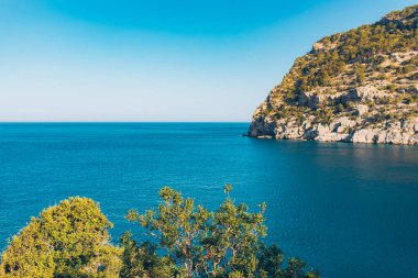 Türkiye 'de güneşli bir günde Akdeniz manzarası. Deniz ve ağaçlarla dolu yaz günü manzarası. Mavi deniz ve dağların gökyüzü manzarası, Akdeniz ya da Ege Denizi. Türkiye 'de tatil ve tatil.