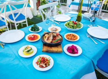 Karides, Deniz Ürünleri, mezeler ve salatalar Fish Restaurant'ta masada. Yunanistan veya Türkiye'de Beach Restaurant. Bodrum, Santorini veya Mikonos'ta Ege sahili, Yunan veya Türk tarzı balık restoranı