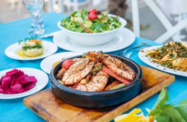 Karides, Deniz Ürünleri, mezeler ve salatalar Fish Restaurant'ta masada. Yunanistan veya Türkiye'de Beach Restaurant. Bodrum, Santorini veya Mikonos'ta Ege sahili, Yunan veya Türk tarzı balık restoranı