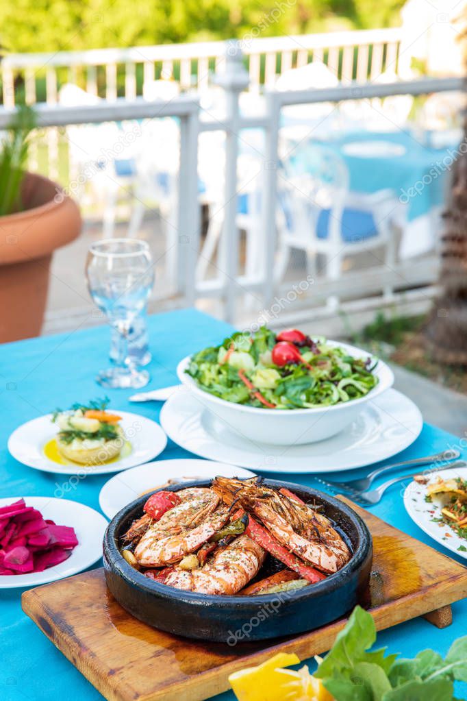 Shrimp, Seafoods, appetizers and salads on the table in Fish Restaurant. Beach Restaurant in Greece or Turkey. Aegean seaside, Greek or Turkish style fish restaurant in Bodrum, Santorini or Mykonos