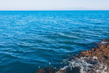 Mavi Okyanus ya da Mavi Deniz, dalgalar ve kayalar. Turkuaz Deniz Dalgaları okyanus ya da denizin kıyılarındaki kayalara çarpıp çarpıyor. Güzel manzaralı doğa manzarası.
