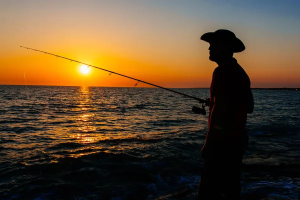 Σιλουέτα Του Fisherman Στέκεται Και Ρίξει Ένα Καλάμι Ψαρέματος Ενώ — Φωτογραφία Αρχείου