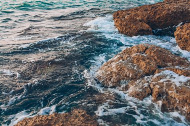Mavi Okyanus ya da Mavi Deniz, dalgalar ve kayalar. Turkuaz Deniz Dalgaları okyanus ya da denizin kıyılarındaki kayalara çarpıp çarpıyor. Güzel manzaralı doğa manzarası.