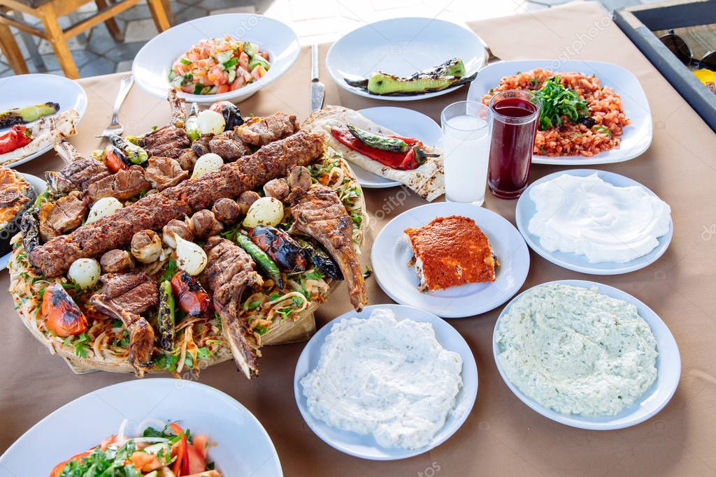 Traditional Turkish Adana Kebab with salads, appetizers, raki and salgam. Turkish Cuisine Dining Dinner Table in Turkish Restaurant. This is Turkish food culture in Turkish Restaurant.