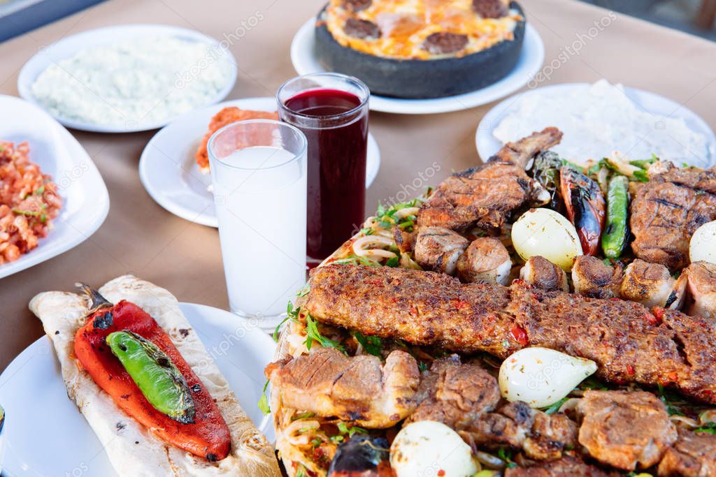 Traditional Turkish Adana Kebab with salads, appetizers, raki and salgam. Turkish Cuisine Dining Dinner Table in Turkish Restaurant. This is Turkish food culture in Turkish Restaurant.
