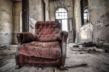 Eski ve yıpranmış kırmızı koltuk terk edilmiş evde.