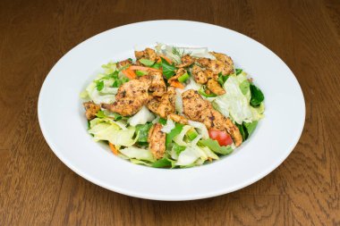 Taze ızgara tavuk salatası ve ahşap masada yeşil sebzeler..