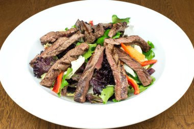 Sebzeli tabakta yemek için Asya usulü kızarmış biftek ya da ızgara yeşil salata. Sağlıklı beslenme yemeği. Tabakta biftek salatası.