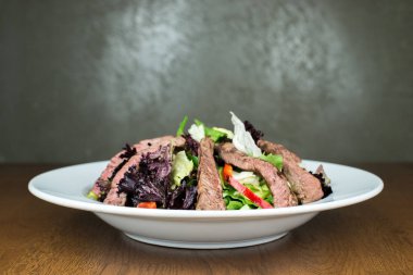 Sebzeli tabakta yemek için Asya usulü kızarmış biftek ya da ızgara yeşil salata. Sağlıklı beslenme yemeği. Tabakta biftek salatası.