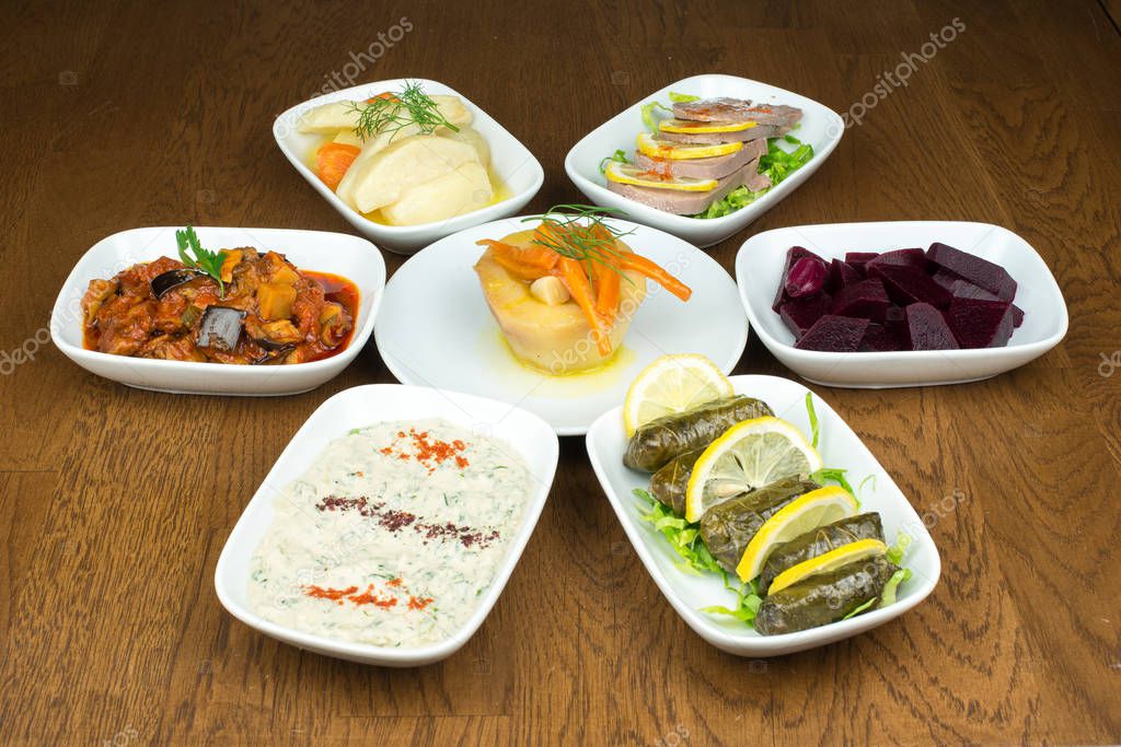 Traditional Turkish or greek appetizers in plate on wooden table surface.
