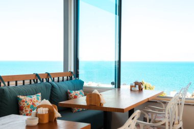 Bodrum 'un Gumusluk plajındaki restoran veya kafe manzarası. Güzel Ege Denizi yakınlarındaki Bodrum kasabasında Ege tarzı renkli sandalyeler, masalar ve çiçekler.