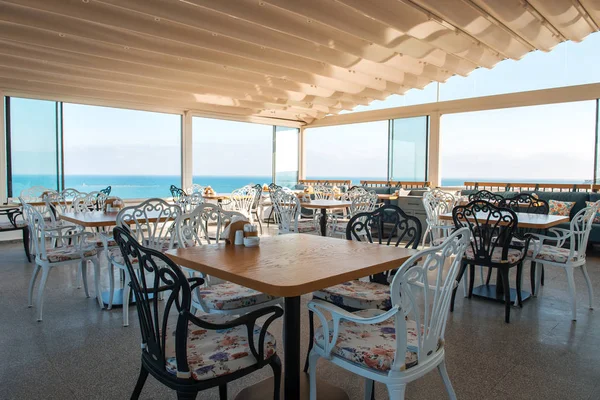 Bodrum 'un Gumusluk plajındaki restoran veya kafe manzarası. Güzel Ege Denizi yakınlarındaki Bodrum kasabasında Ege tarzı renkli sandalyeler, masalar ve çiçekler.