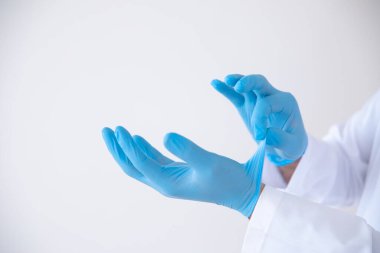 Doktor, Covid-19, 2019-NCoV ya da Coronavirus 'un yayılmasını önlemek için steril ameliyat eldivenlerini düzgün bir şekilde çıkarıyor ya da çıkarıyor.