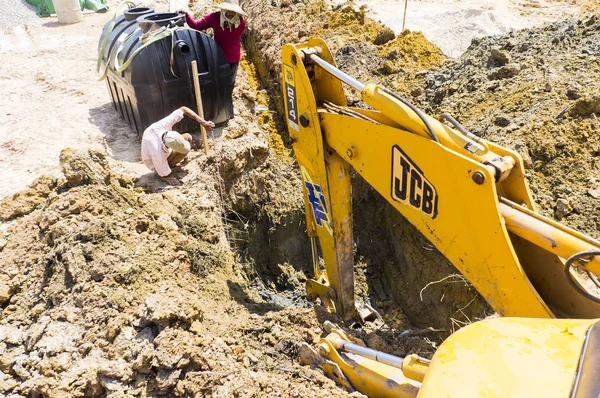 液压挖掘机在施工现场工作 免版税图库照片