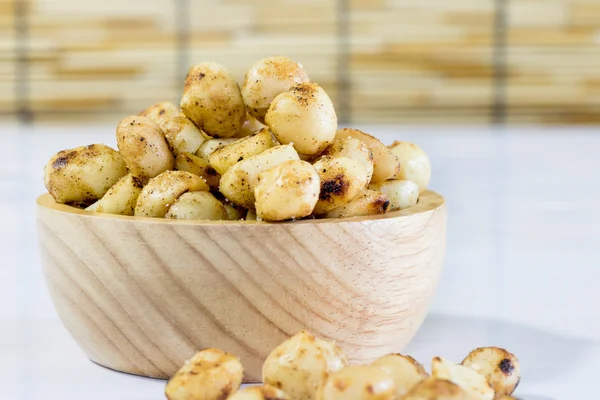 Macadamia cuit avec du sel dans un bol en bois sur une table blanche — Photo