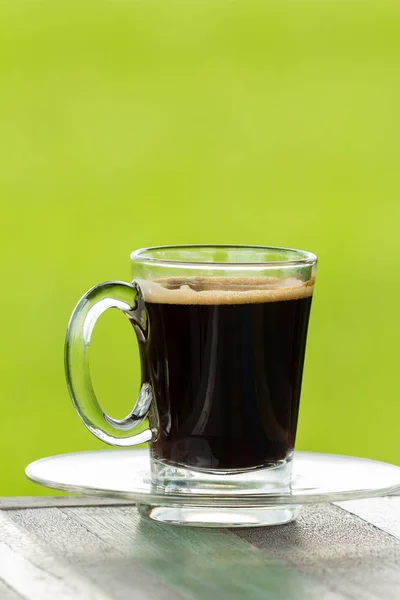 Café negro caliente sobre mesa de madera con fondo verde de la naturaleza — Foto de Stock