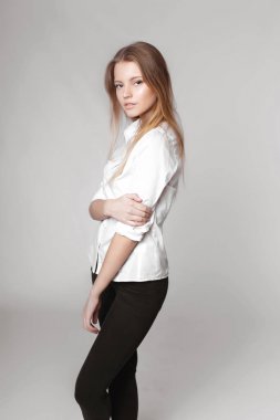 Aydınlık, geniş Studio'da şık rahat ve basit elbise gri bir arka plan ile poz bir kızın moda portre. temiz cilt ve mükemmel yüz genç kızla 