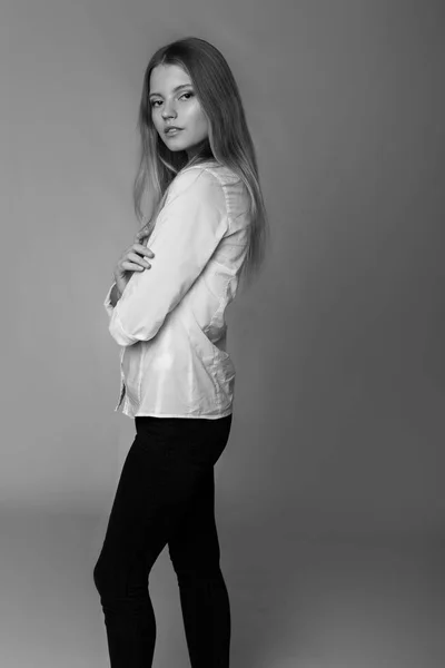 Mode portret van een meisje poseren in lichte, ruime studio met een grijze achtergrond in een stijlvolle, comfortabele en eenvoudige kleren. jong meisje met schone huid en perfecte gezicht — Stockfoto
