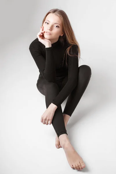 Retrato de moda de una chica posando en un estudio amplio y luminoso con un fondo gris en una ropa cómoda y sencilla con estilo. chica joven con la piel limpia y la cara perfecta —  Fotos de Stock