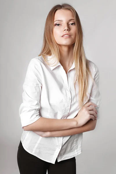 Modeporträt eines Mädchens posiert in hellem, geräumigem Studio mit grauem Hintergrund in stilvoller, bequemer und einfacher Kleidung. junges Mädchen mit sauberer Haut und perfektem Gesicht — Stockfoto