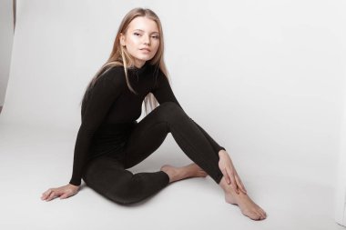 Aydınlık, geniş Studio'da şık rahat ve basit elbise gri bir arka plan ile poz bir kızın moda portre. temiz cilt ve mükemmel yüz genç kızla 
