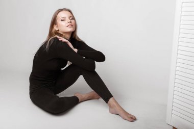 Aydınlık, geniş Studio'da şık rahat ve basit elbise gri bir arka plan ile poz bir kızın moda portre. temiz cilt ve mükemmel yüz genç kızla 