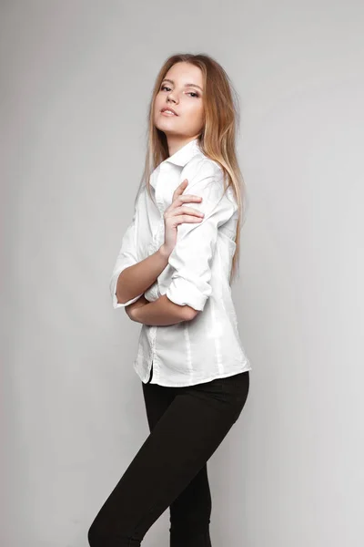 Mode Porträtt av en flicka som poserar i ljusa, rymliga studio med en grå bakgrund i en snygg bekväm och enkel kläder. ung flicka med ren hud och perfekt ansikte — Stockfoto