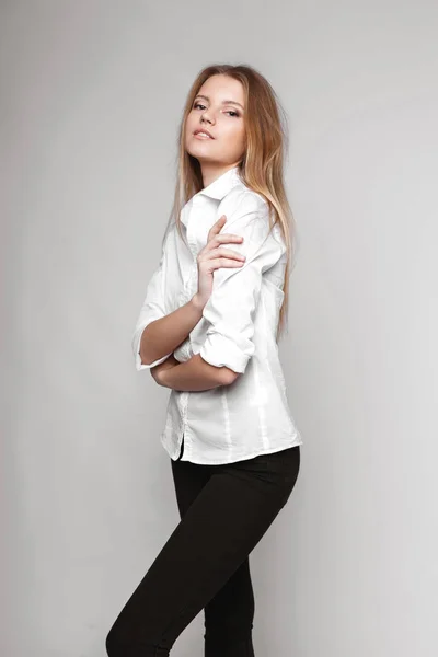 Retrato de moda de una chica posando en un estudio amplio y luminoso con un fondo gris en una ropa cómoda y sencilla con estilo. chica joven con la piel limpia y la cara perfecta —  Fotos de Stock