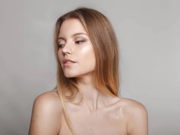 Retrato de moda de una chica posando en un estudio amplio y luminoso con un fondo gris en una ropa cómoda y sencilla con estilo. chica joven con la piel limpia y la cara perfecta —  Fotos de Stock