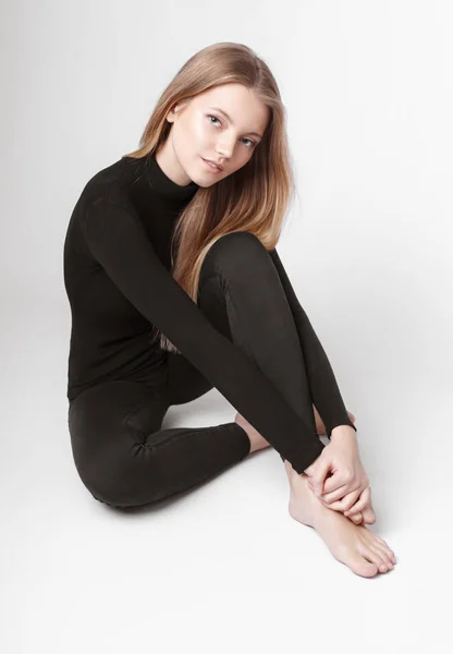 Retrato de moda de una chica posando en un estudio amplio y luminoso con un fondo gris en una ropa cómoda y sencilla con estilo. chica joven con la piel limpia y la cara perfecta —  Fotos de Stock