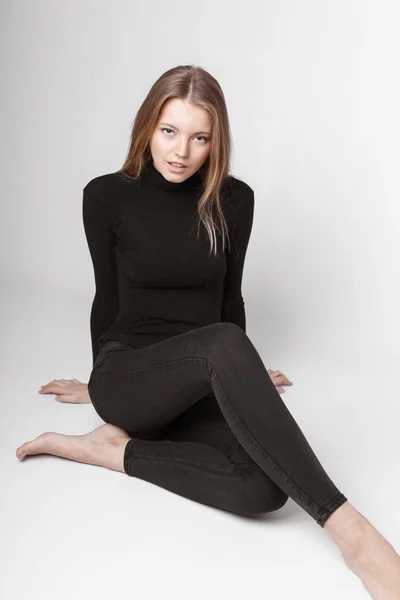 Retrato de moda de una chica posando en un estudio amplio y luminoso con un fondo gris en una ropa cómoda y sencilla con estilo. chica joven con la piel limpia y la cara perfecta —  Fotos de Stock