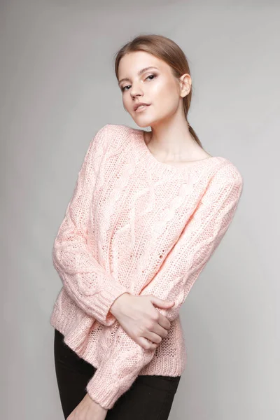 Retrato de moda de uma menina posando em estúdio brilhante e espaçoso com um fundo cinza em uma roupa elegante confortável e simples. jovem com pele limpa e rosto perfeito Fotografia De Stock